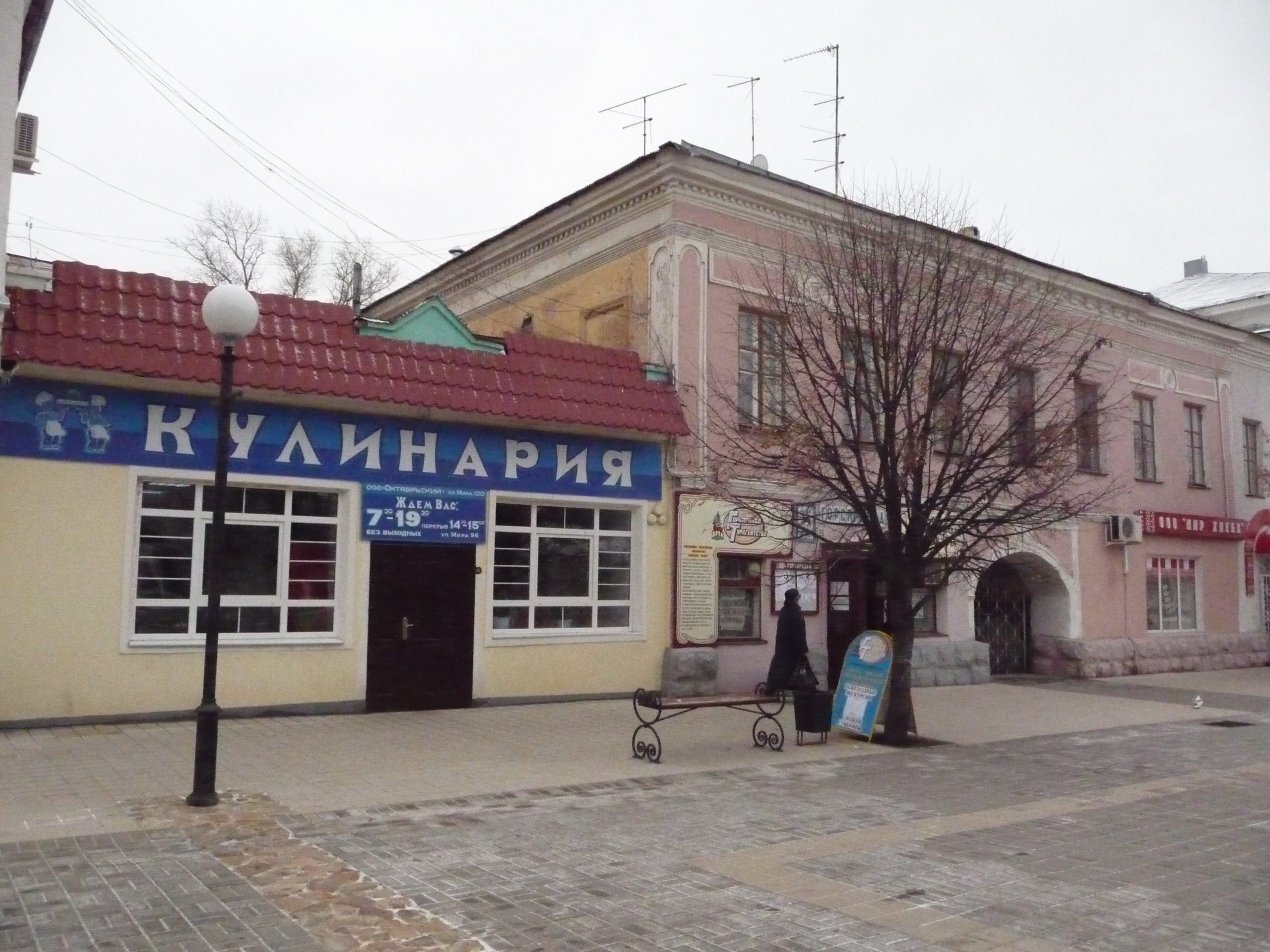 Двухэтажный дом с арочным проездом на Мира, 96 и примыкающая слева одноэтажная лавка с вывеской кулинарии.